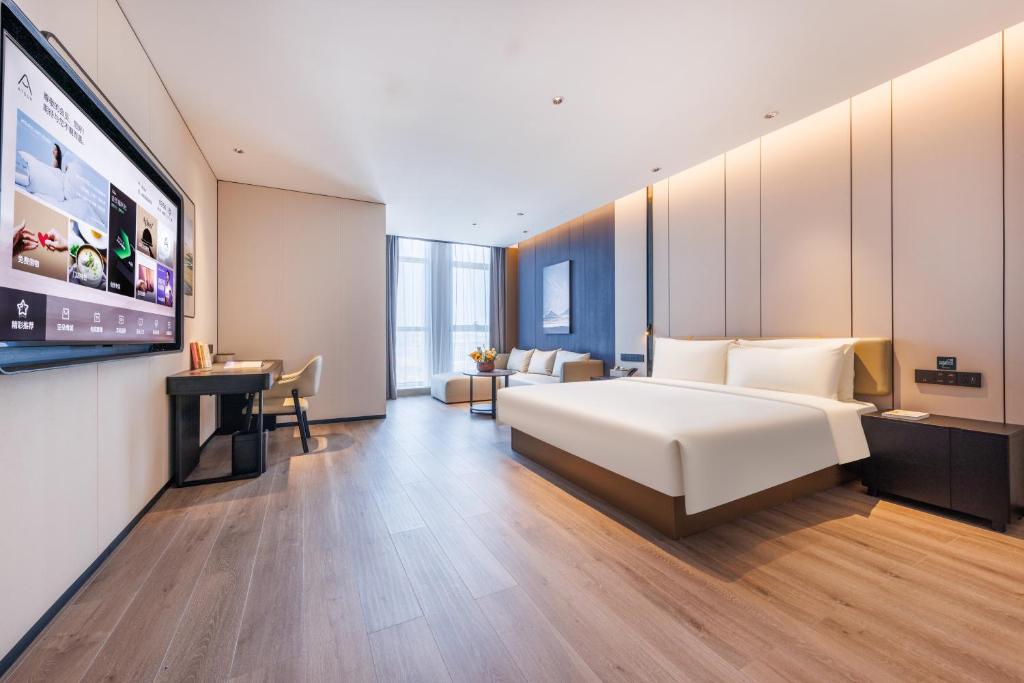 une chambre d'hôtel avec un lit et une télévision à écran plat dans l'établissement Atour Hotel Yantai Bajiaowan University Town, à Yantai