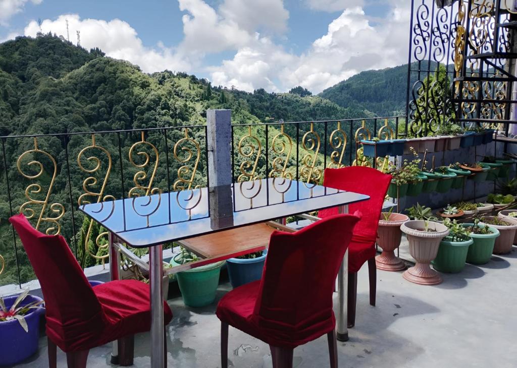 een tafel en stoelen op een balkon met uitzicht bij Mountain Paradise Homestay BATASIA LOOP in Darjeeling