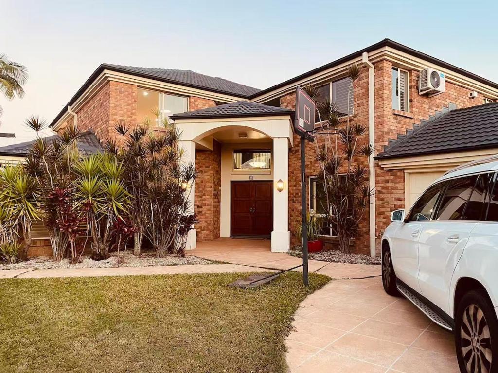 a white car parked in front of a brick house at Spacious Family Retreat with Pool in Carindale in Brisbane