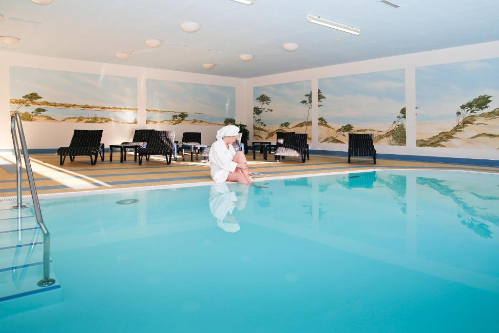 a person is standing in the water next to a swimming pool at Landhaus Am Grün in Kühlungsborn