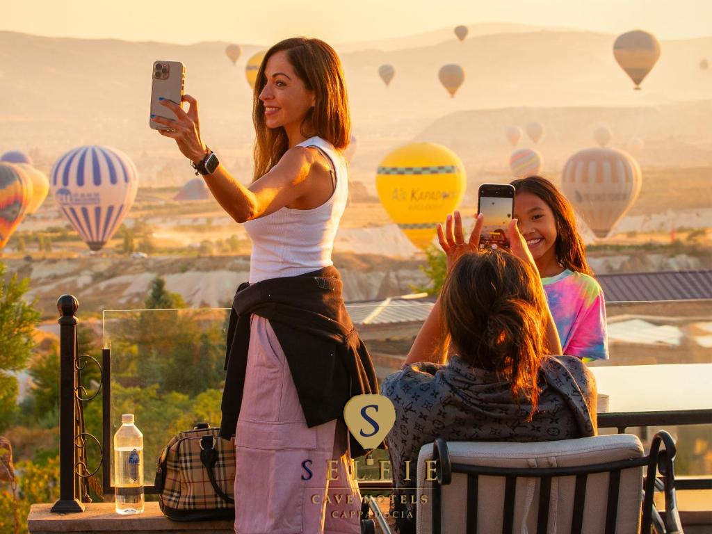 una donna che scatta una foto ad alcune mongolfiere di Cappadocia Fairy Chimneys Selfie Cave Hotels - Special Class a Üçhisar