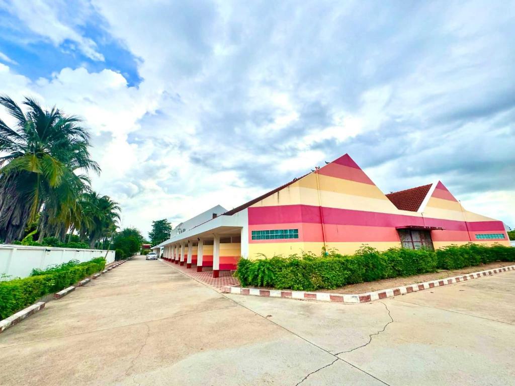 a colorful building with a palm tree in front of it at OYO 75583 Fut Fit Fo Fai Inn Hotel in Kanchanaburi