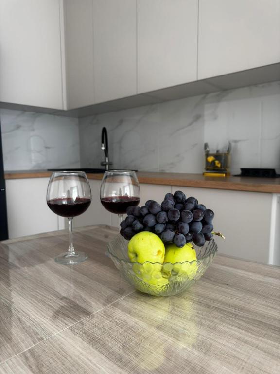 dos copas de vino y un bol de fruta en una mesa en Апартамент, en Uralsk