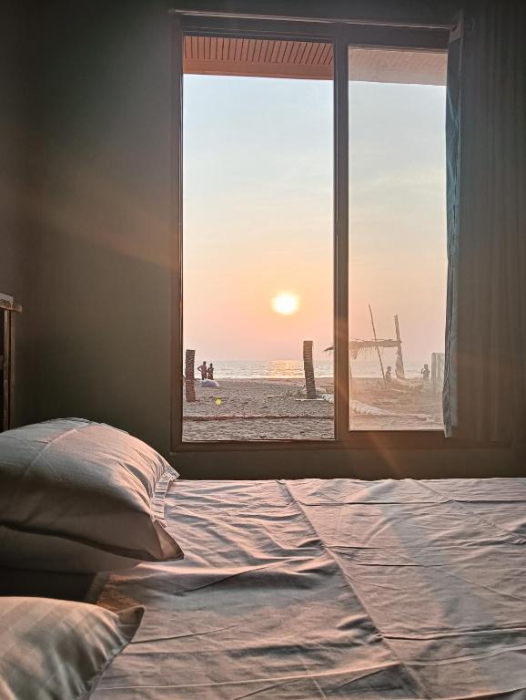 a bedroom with a window view of the beach at Lakshika beach resort in Gokarna