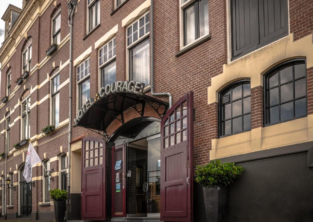 a red brick building with a garage on a street at Hotel Courage Waalkade in Nijmegen