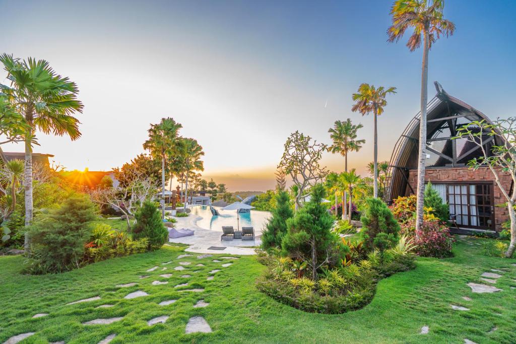 a garden with palm trees and a building at Cemara Hills Uluwatu, The Reserve - Cottages & Villas in Uluwatu