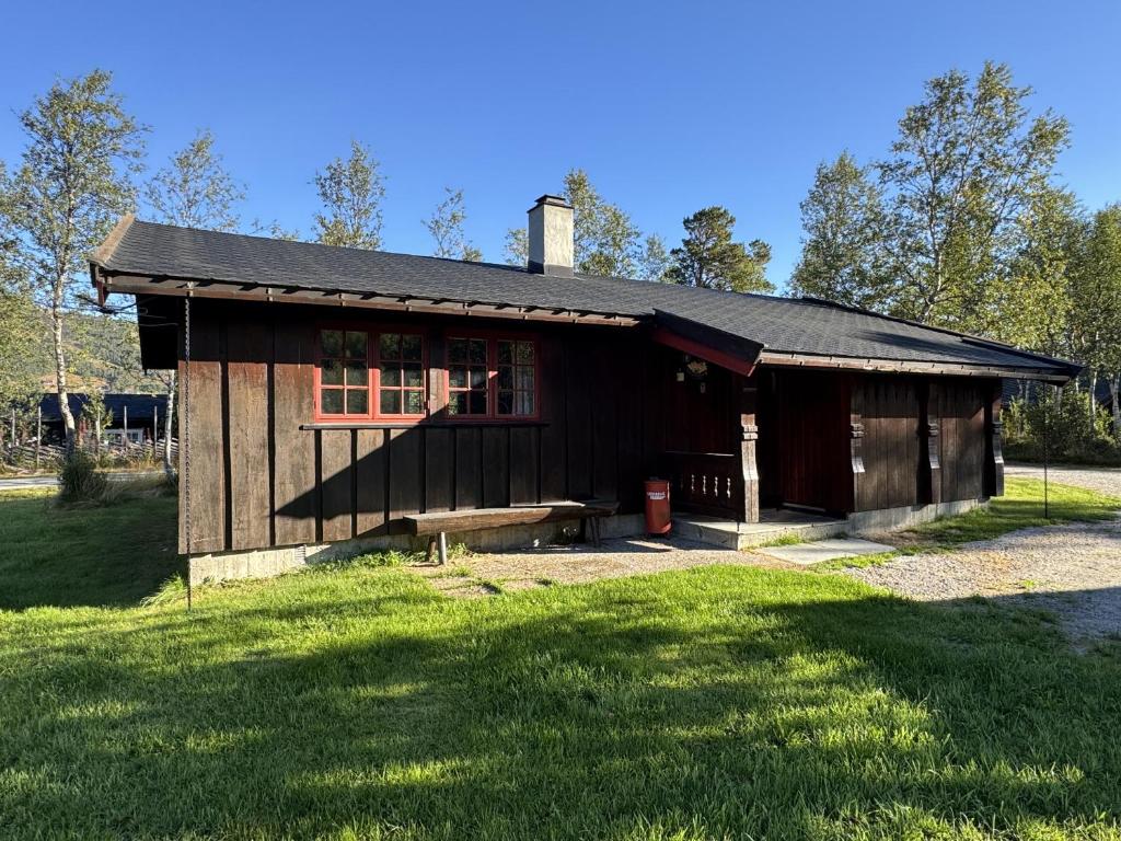 a wooden cabin with a bench in the grass at Briskebu, cosy cabin by ski slopes in Geilo