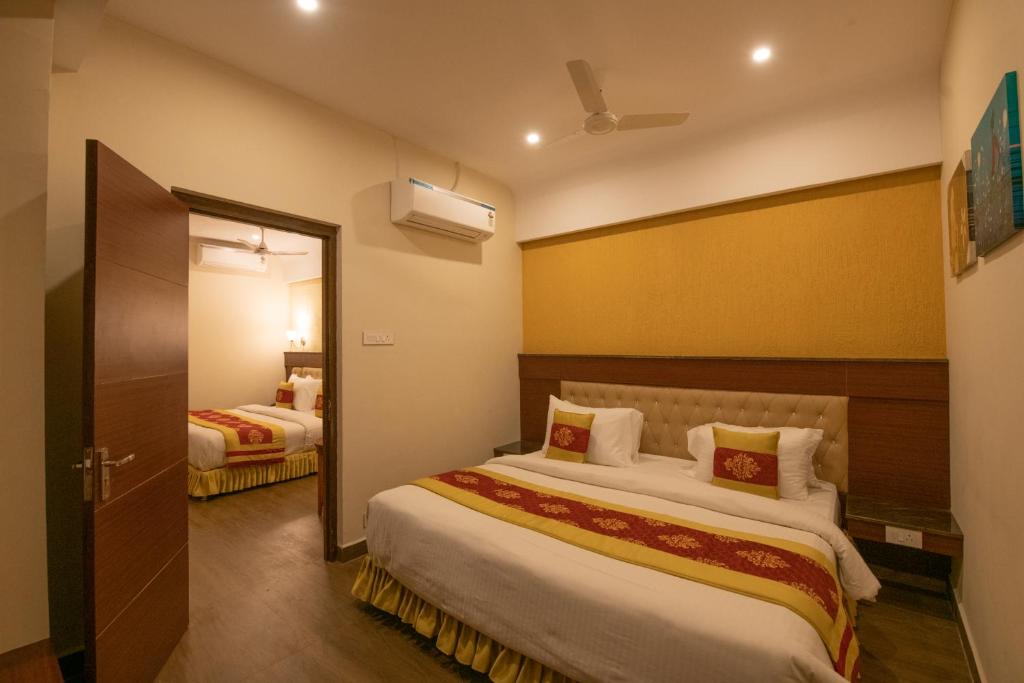 a hotel room with two beds and a mirror at Hotel High Point in Tiruchchirāppalli