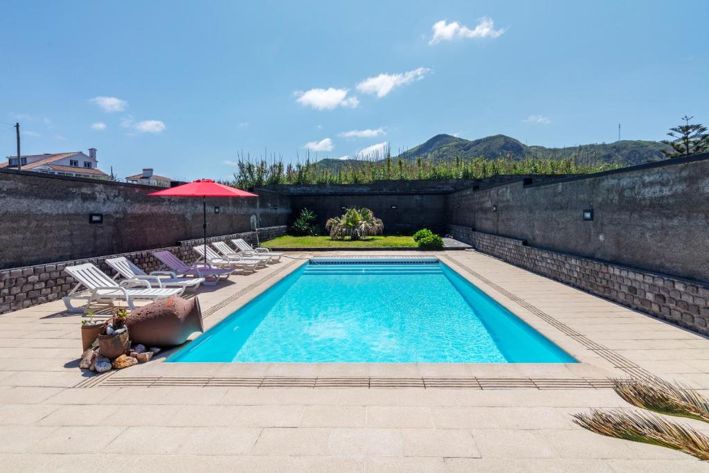 a swimming pool in a yard with chairs and asevere at Refúgio do Sol - Azorean Butler in Mosteiros