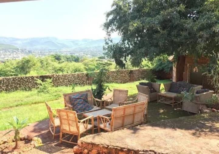 a patio with couches and chairs in a yard at Deans hills view camp site lodge in Chipata