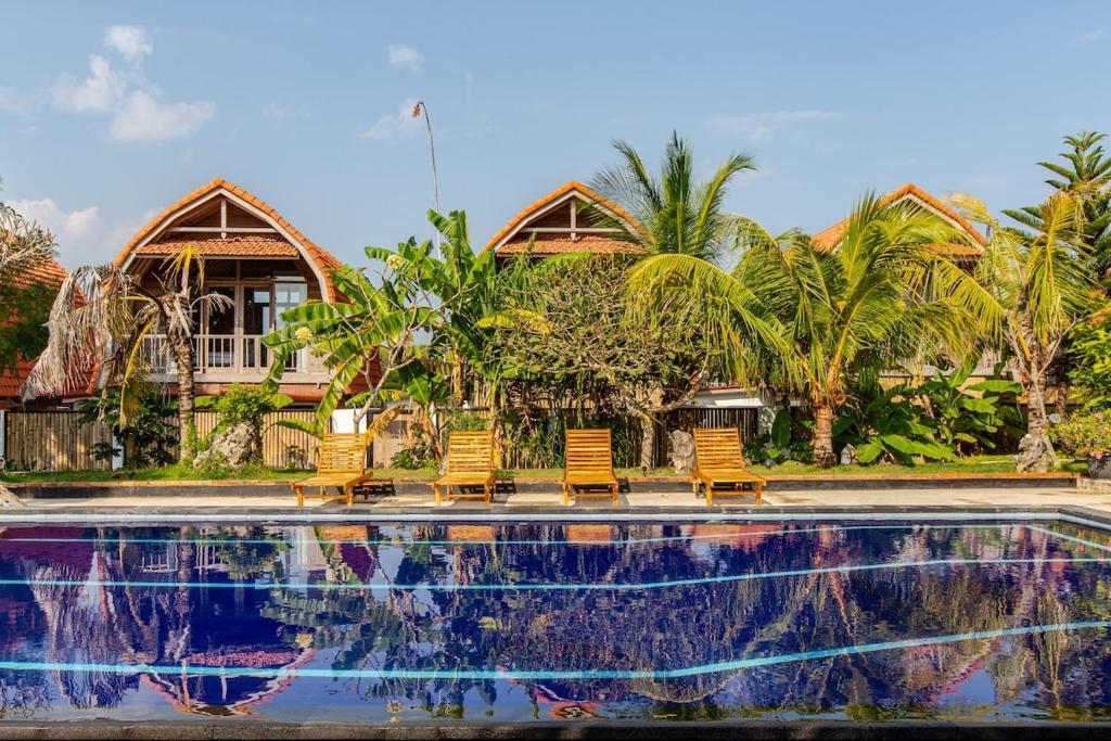 a group of chairs sitting next to a swimming pool at Villa Lumbung Uluwatu 2 in Uluwatu