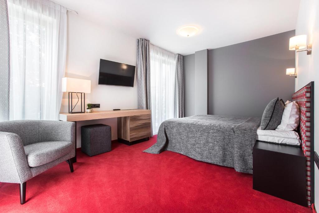 a hotel room with a bed and a desk and a chair at Viešbutis Simpatija in Druskininkai