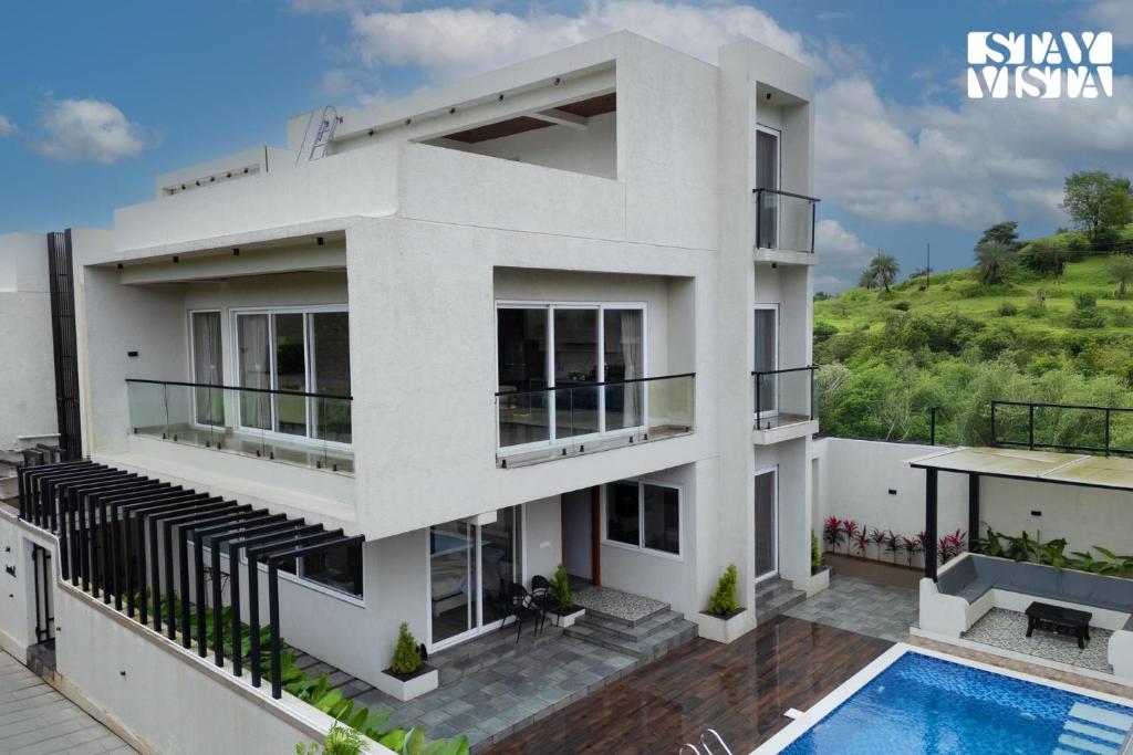 una casa blanca con piscina en StayVista at Oriana Palms with Wifi and Pool, en Igatpuri