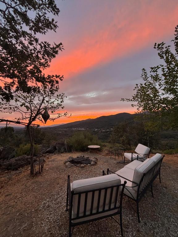 two benches sitting on top of a hill with a sunset at El Encuentro - Casa Rural - in Arenas de San Pedro