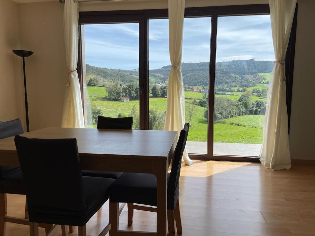 a dining room table with chairs and a large window at Espaciosa con vistas in Villaviciosa