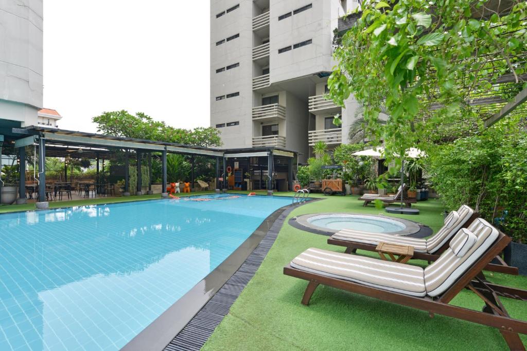 a swimming pool with chaise lounge chairs and a building at Abloom Exclusive Serviced Apartments in Bangkok