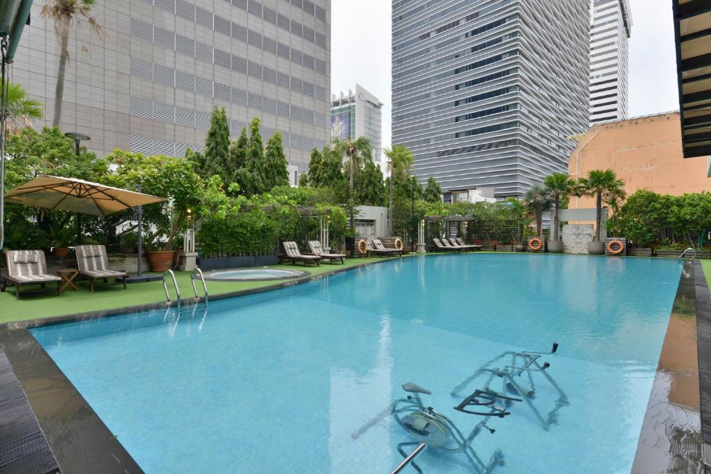 A large outdoor pool surrounded by loungers and city towers.