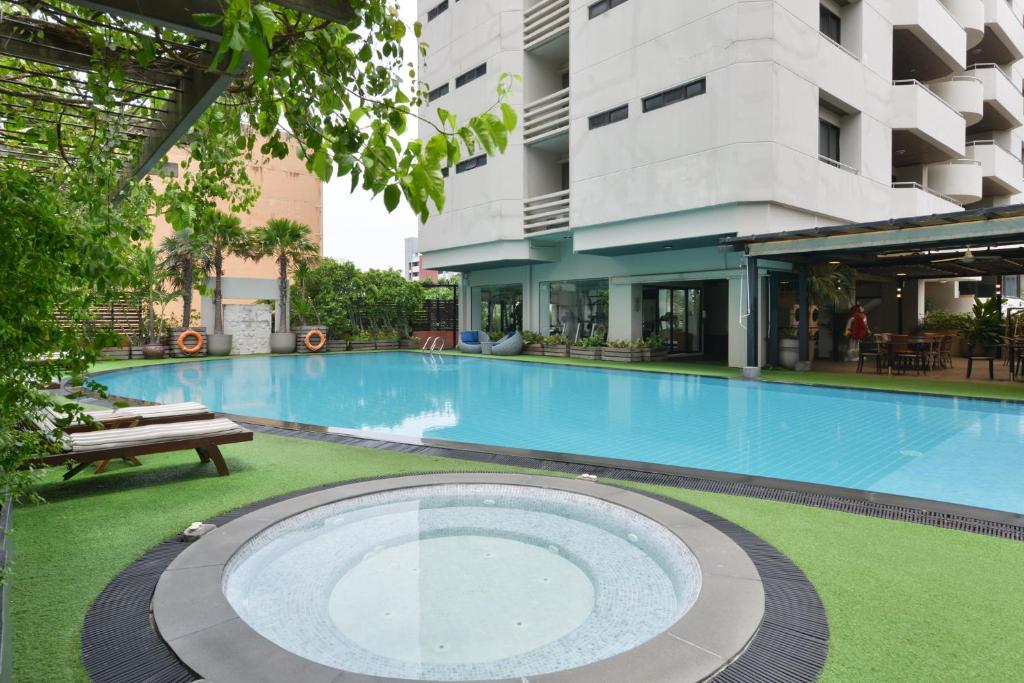A wide pool view showing a circular spa in the foreground and apartment buildings around the deck.
