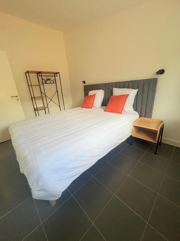 a bedroom with a large white bed with red pillows at Les chambres du Vignoble in Pauillac