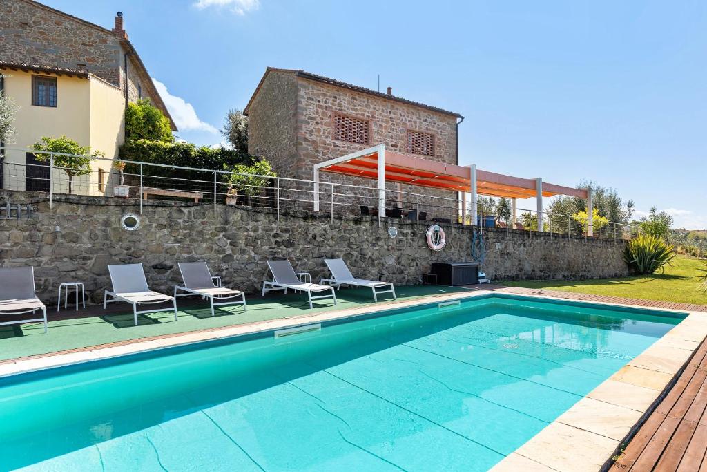 une piscine avec des chaises à côté d'un mur de pierre dans l'établissement Resort Esclusivo di Vinci, à Vinci