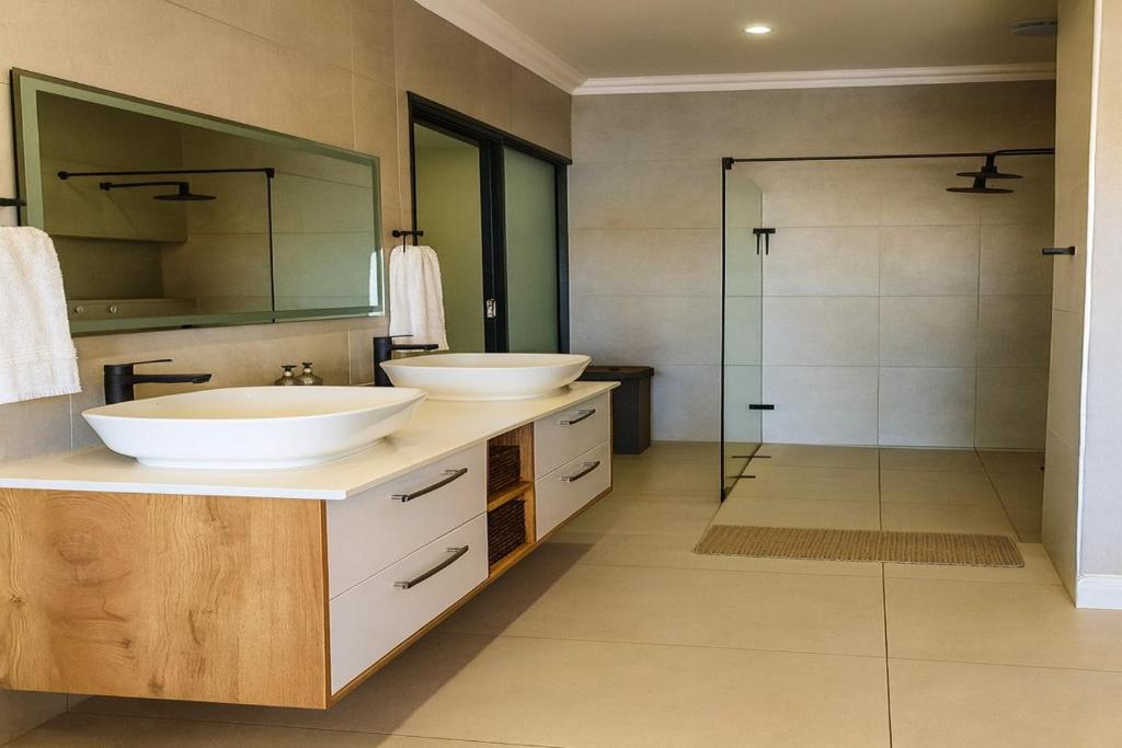 a bathroom with two sinks and a shower at 1442 Marina by Double Portion in Jeffreys Bay