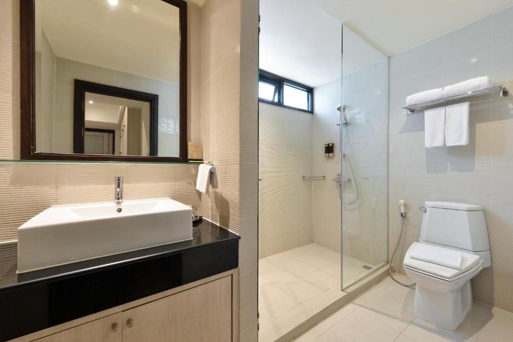 A bright bathroom with a vanity, toilet and separate glass-screened shower.