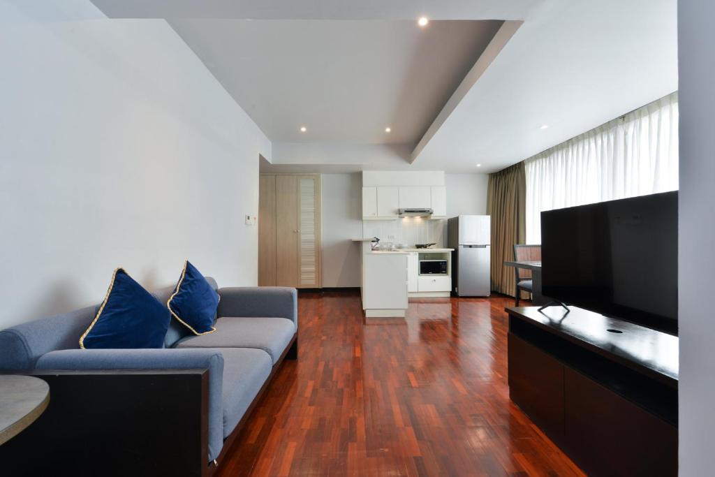 An open-plan living area with a blue sofa, television and full kitchenette.