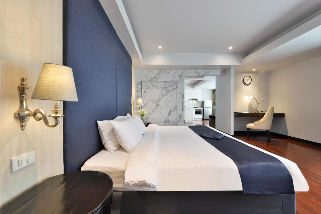A king bedroom with a navy upholstered headboard, marble-look partition and writing desk.