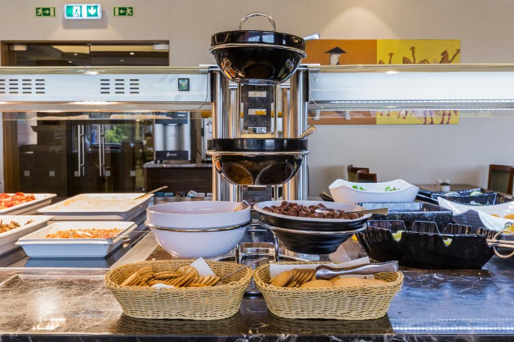 A self-service buffet counter with baskets of bread and bowls of breakfast food.