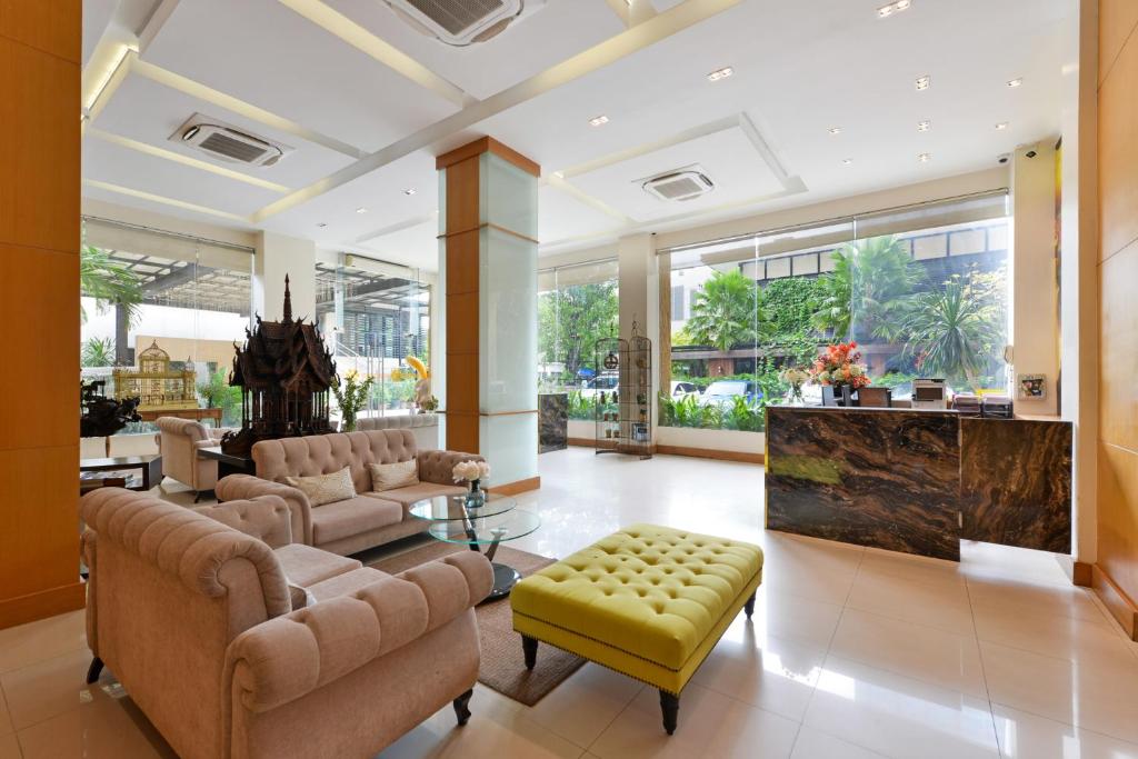 A bright lobby lounge with tufted sofas, a vivid ottoman and a staffed-looking reception desk.