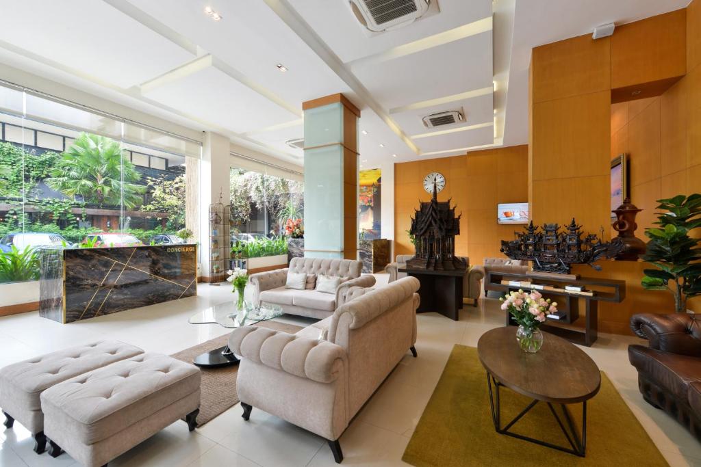 A spacious lounge with upholstered seating, coffee tables and large windows onto greenery.