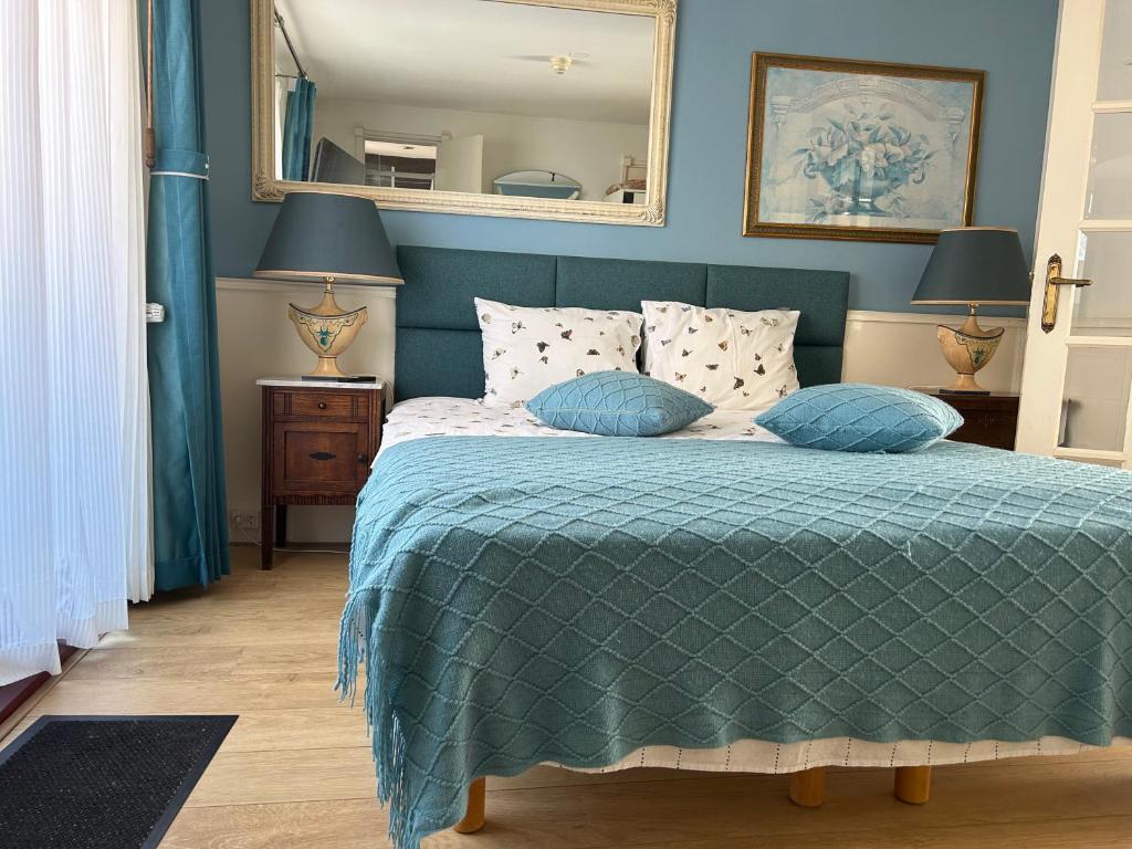 Dormitorio con cama con edredón verde y espejo en Leoicom, en Zandvoort