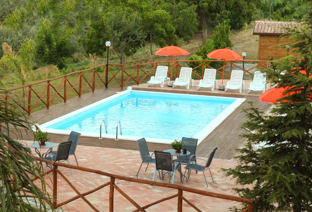 a swimming pool with chairs and tables and umbrellas at La Parrinara in Francavilla di Sicilia