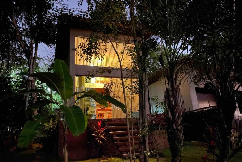 a house with a lit up window at night at The Private Forest Lake Tinys Aruanda in Mata de Sao Joao
