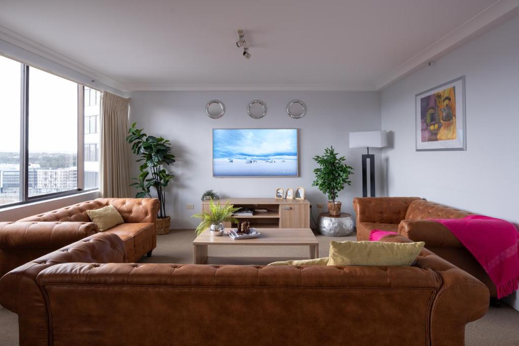 a living room with two brown couches and a tv at Canberra City View Apartment in Canberra