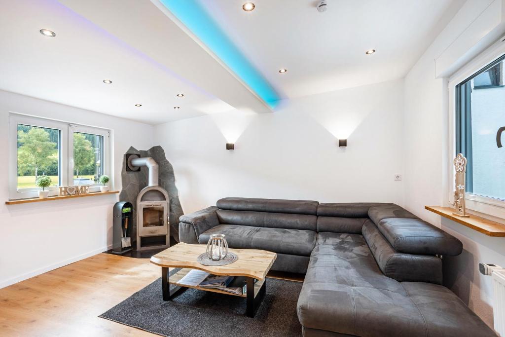 a living room with a leather couch and a table at Ferienwohnung Kurparkblicksauerland in Lennestadt