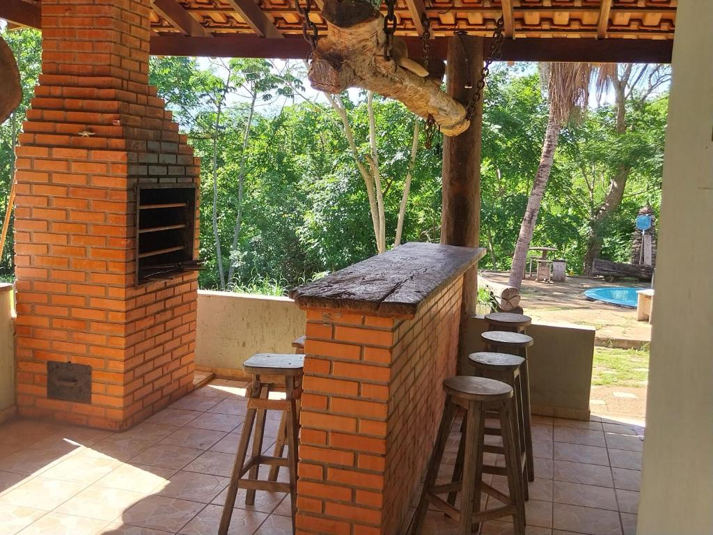 Un bar al aire libre con taburetes y un horno de ladrillo. en Chácara PontAlegre, en Rondonópolis