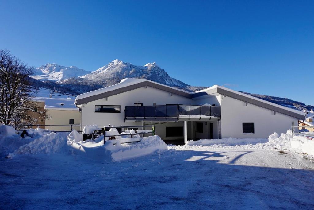 a house covered in snow with mountains in the background at Casa Stella in Cunter