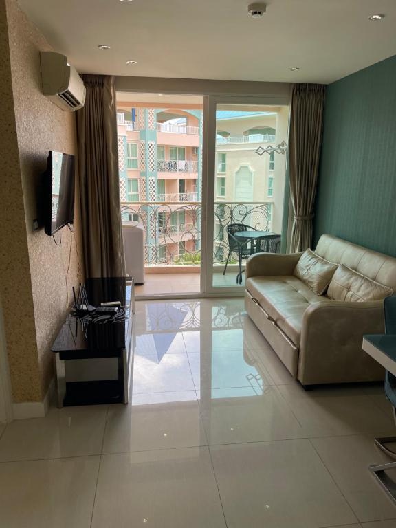 パタヤ・サウスにあるgrande caribbean condo by stays innのソファとバルコニーのあるリビングルーム