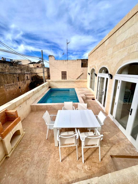 a white table and chairs on a patio with a pool at Ta' Marija in Sannat