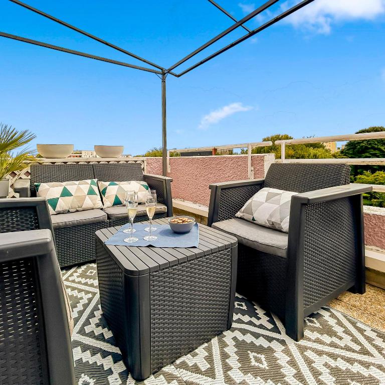 a patio with wicker chairs and a table with wine glasses at Proche Paris et Disneyland T2 calme avec Terrasse in Noisiel