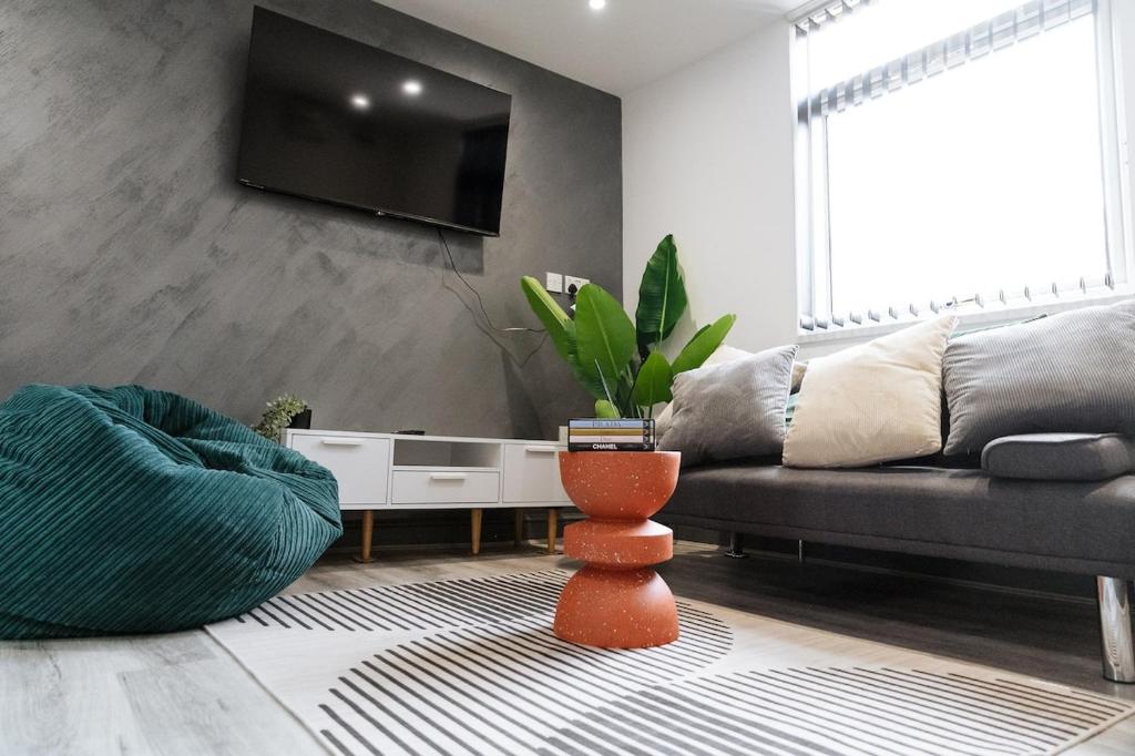 a living room with a couch and a tv on a wall at 4x Studio Apartments for Contractors, Professionals and Families near Coventry University, City Centre, BHX & NEC in Coventry