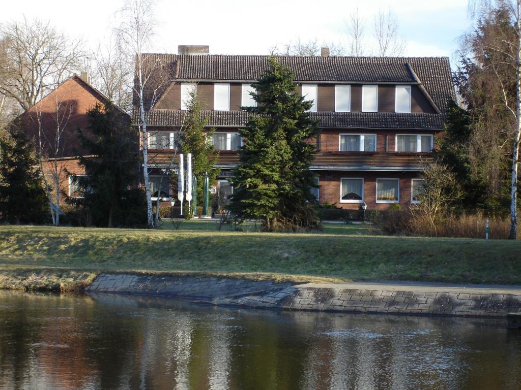 un bâtiment à côté d'une rivière en face d'un bâtiment dans l'établissement Landgasthof Allerparadies, à Langlingen