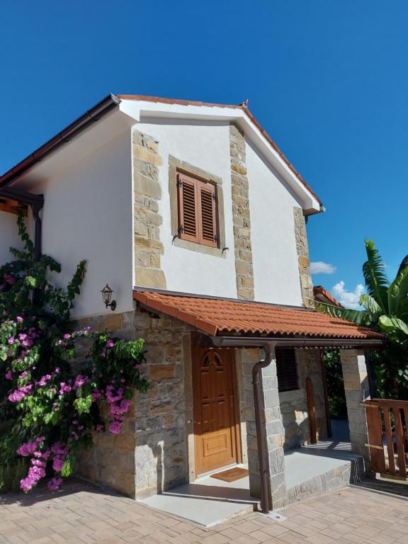 a small white house with a brown door at Istrska kamnita hiša z velikim vrtom - Istrian Stone House with Big Garden in Marezige