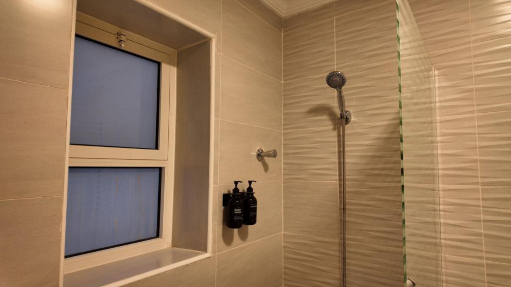 La salle de bains est pourvue d'une douche et d'une fenêtre. dans l'établissement 3 Serenity U Private Residence, à Khobar