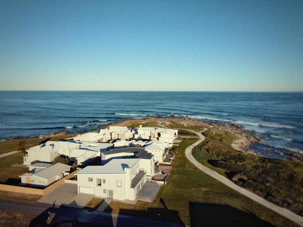 an aerial view of a group of white houses by the ocean at Agapé Villa Agulhas in Agulhas