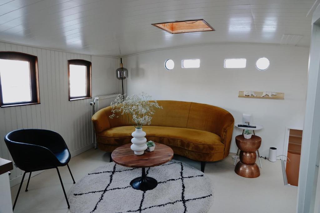 una sala de estar con un sofá y una mesa en City center Amstel river Houseboat Kom en Zie, en Ámsterdam