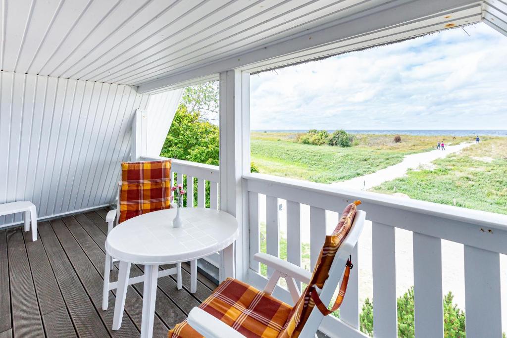 a porch with a table and chairs and a view of the ocean at Strandhaus Claassen 08 in Ahrenshoop