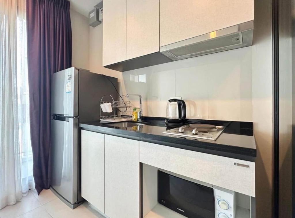 Pattaya the base condo في باتايا سنترال: مطبخ مع موقد وثلاجة