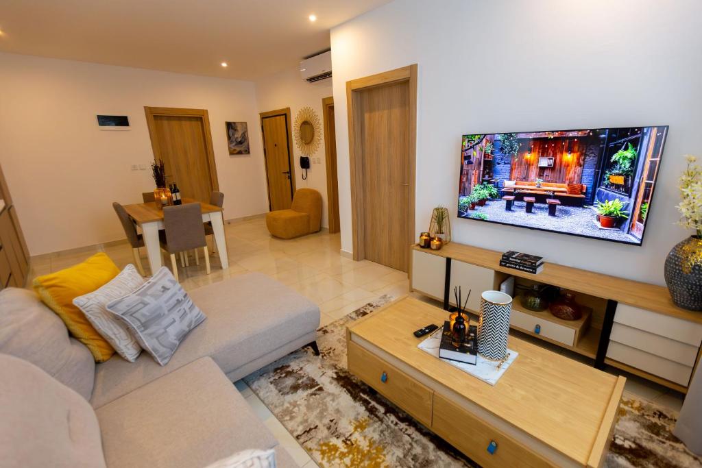 a living room with a couch and a flat screen tv at Stylish Apartment with Modern Amenities in Nova Roman Ridge in Accra